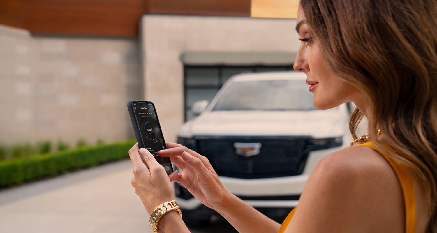 lady checking her mobile with a Cadillac vehicle background | Ryan Cadillac in Buffalo MN